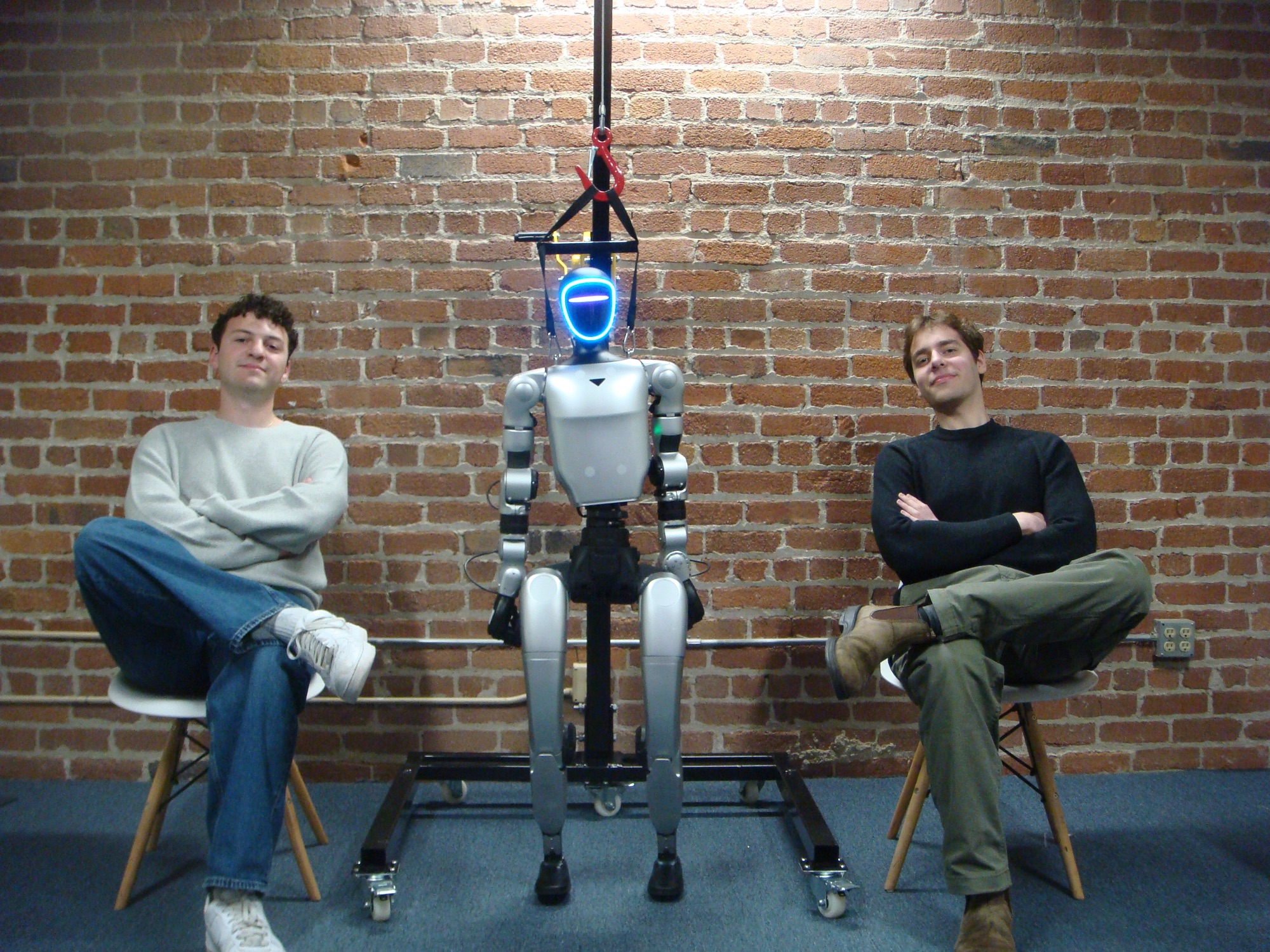 Two people seated beside a humanoid robot